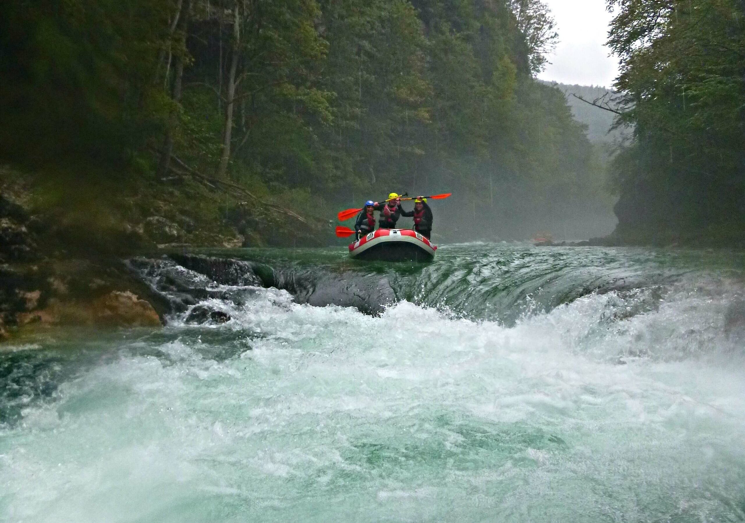 Trois personnes font du canoé sur une rivière entouré de foret