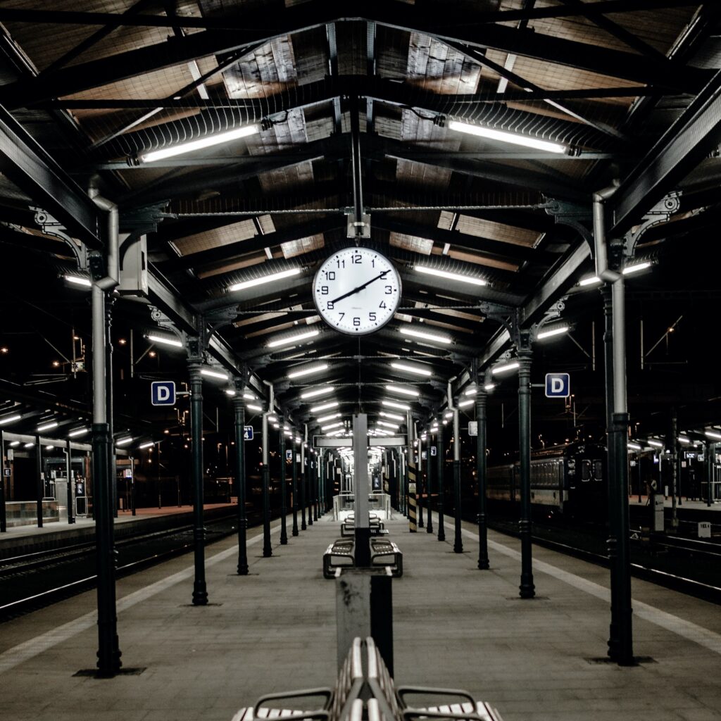 Une gare de nuit où l'on a une grosse horloge bien colorer 